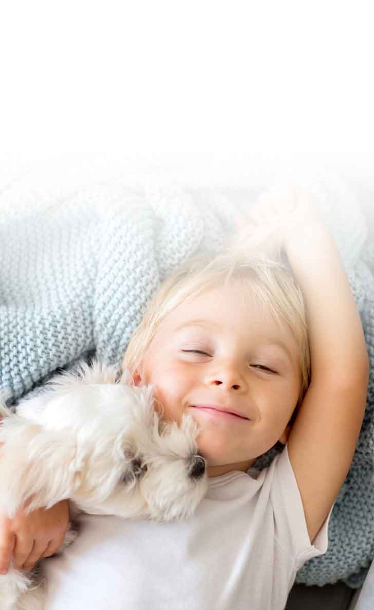 kind-liegt-mit-hund-auf-decke